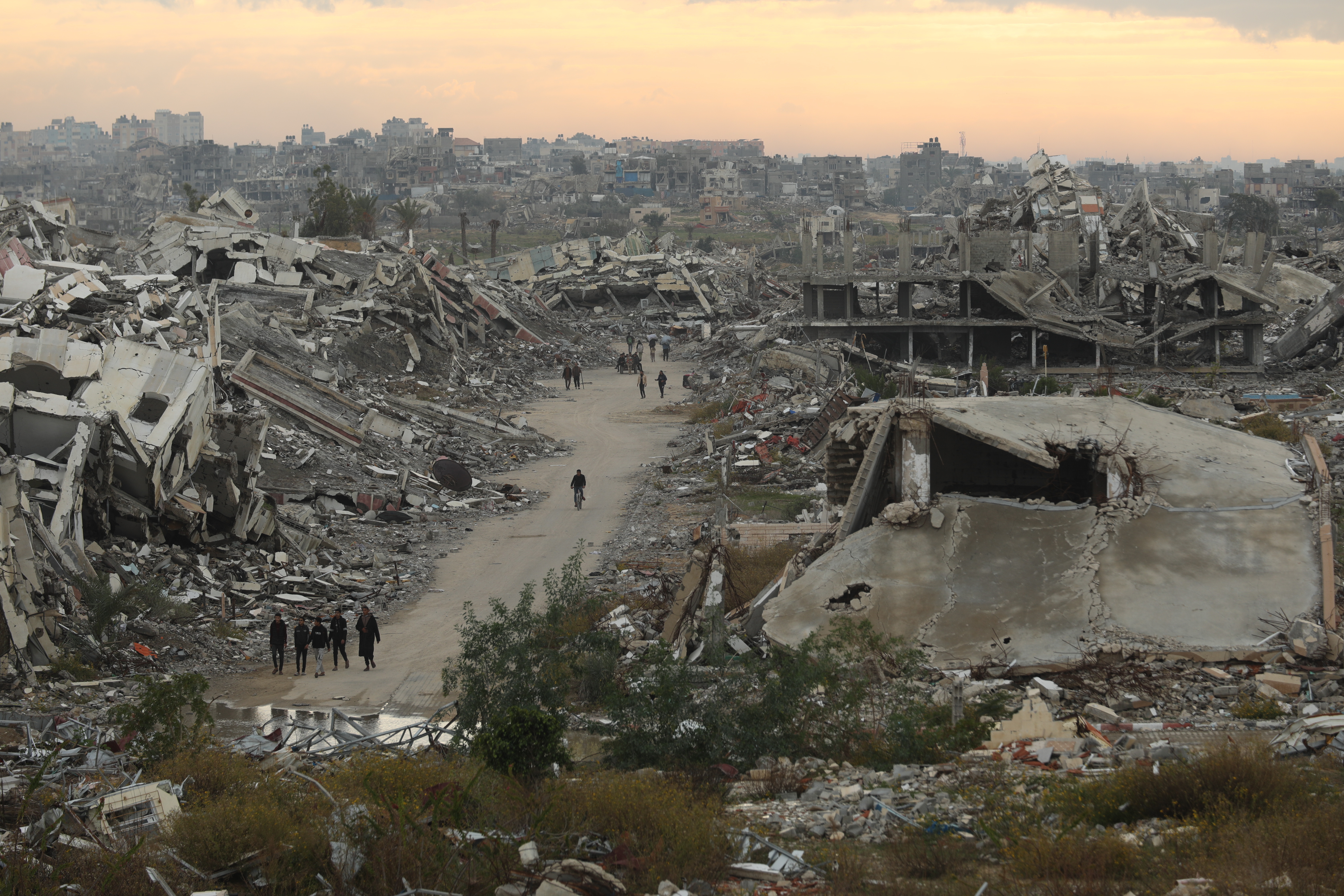 GAZA CITY, GAZA  â" DECEMBER 19: Palestinians walk through roads surrounded by massive rubble and collapsed buildings in Al-Zahra, northwest of the Nuseirat Refugee Camp in the central Gaza Strip, as residents continue their daily lives amid the destruction left by Israeli attacks, facing harsh living conditions on December 19, 2025. (Photo by Hassan Jedi/Anadolu via Getty Images)