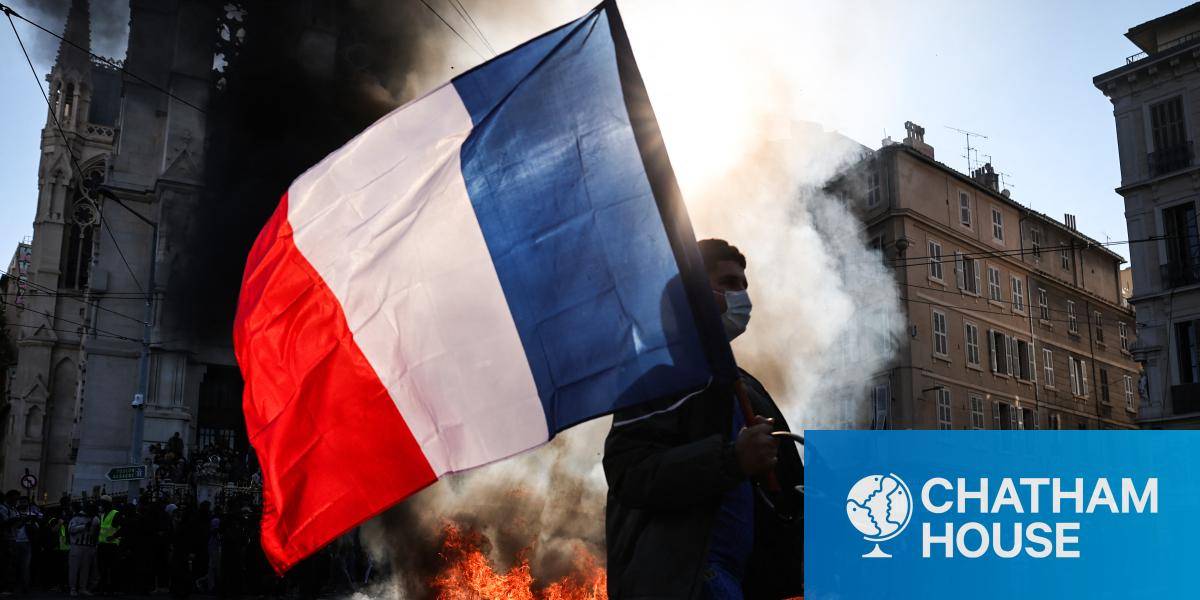 A protester waves a French flag during clashes in Marseille, a fire burning behind