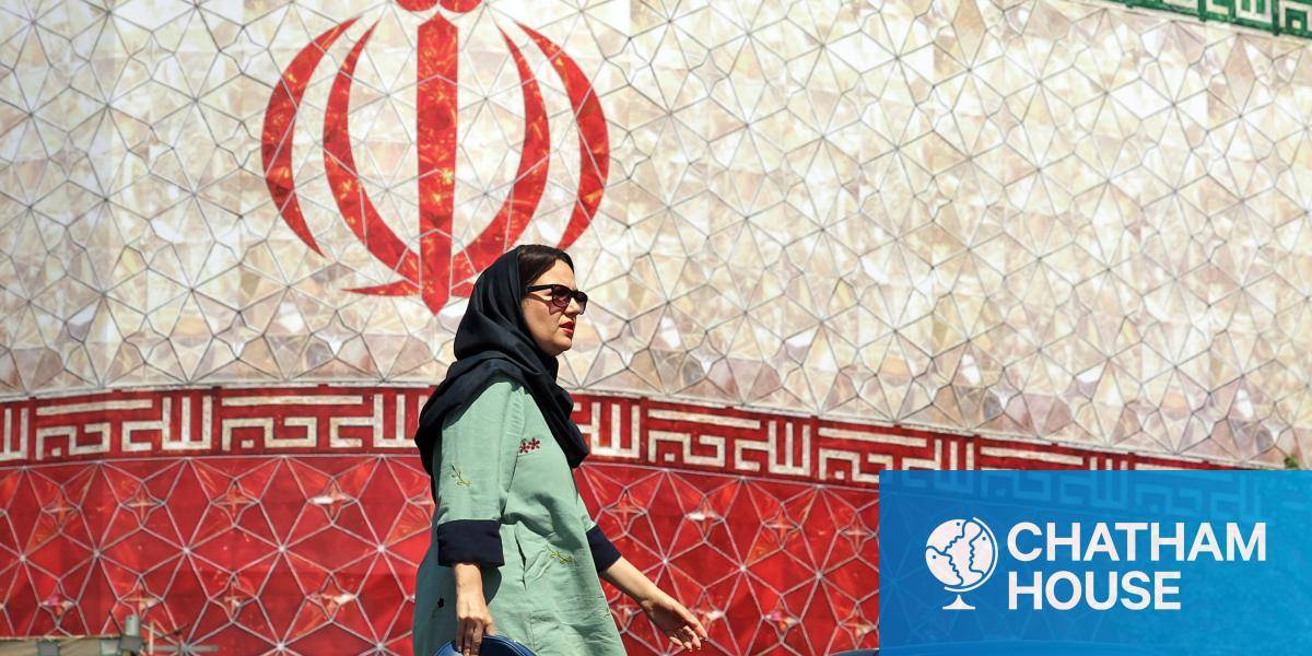 An woman walks past a billboard displaying Iran's national flag at Enghelab Square in Tehran on June 14, 2026. 