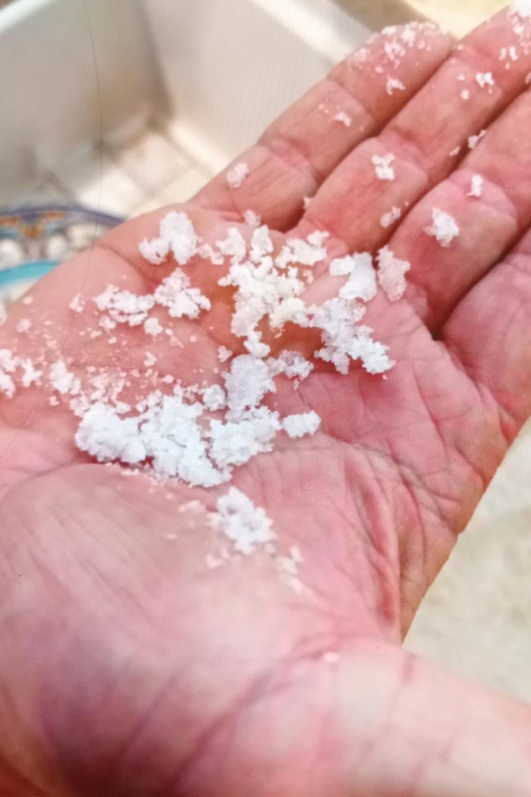 A hand with large chunks of salt clustered on the palm.